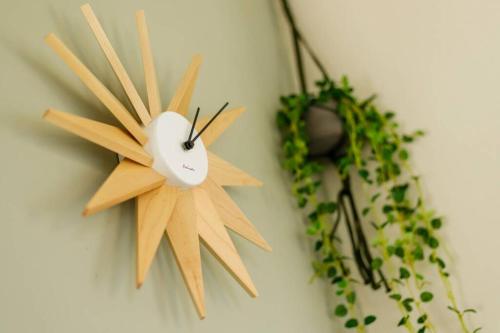 a wooden clock on a wall with some plants at Beach House Villa Kashima in Kashima