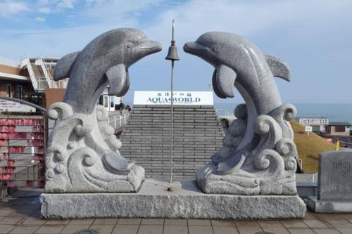 a statue of dolphins in front of a building at Beach House Villa Kashima in Kashima