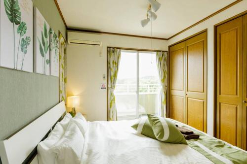 a bedroom with a white bed and a window at Beach House Villa Kashima in Kashima