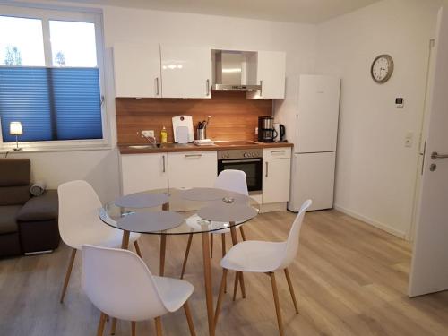 a kitchen with a table and white chairs in a room at WH Boardinghouse in Papenburg