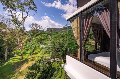 a balcony with a bed and a view of a field at Sementra Hot Spring Nature Resort in Gopeng