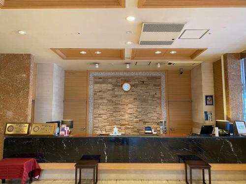 a lobby with a counter and a brick wall at Koriyama View Hotel in Koriyama