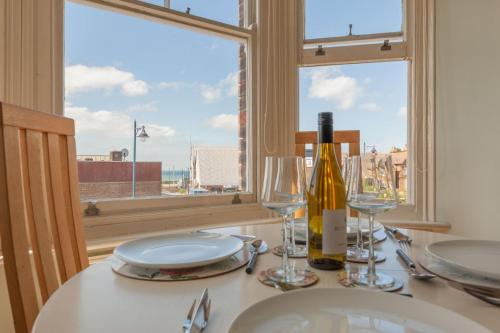 a table with glasses and a bottle of wine at Pilgrim's Lookout Whitstable Holiday Home in Whitstable