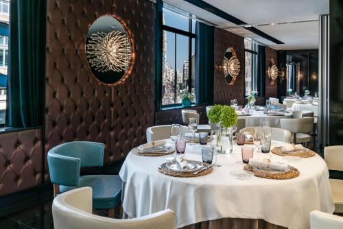 a restaurant with white tables and chairs and windows at Vincci Capitol in Madrid