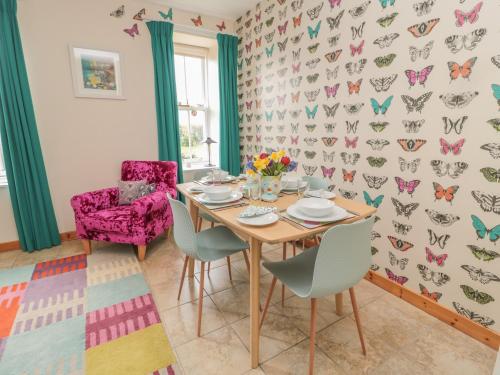 a dining room with a table and chairs and a butterfly wallpaper at Adams House in Eyemouth