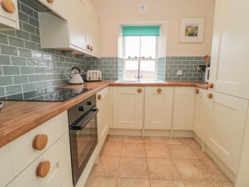 a kitchen with white cabinets and a window at Adams House in Eyemouth