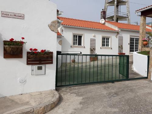 a white house with a gate with red flowers at Casa Branca do Moinho in Salgueiro