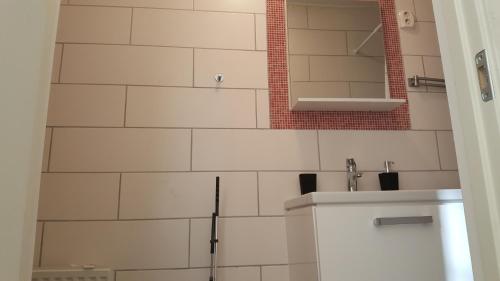 a white tiled bathroom with a sink and a mirror at SJÖTORPS HOSTEL in Sjötorp
