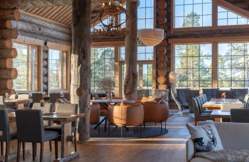 a restaurant with tables and chairs and windows at Wilderness Hotel Nangu & Igloos in Ivalo