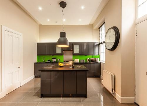 a kitchen with black cabinets and a clock on the wall at Nelson Manor in Dundee