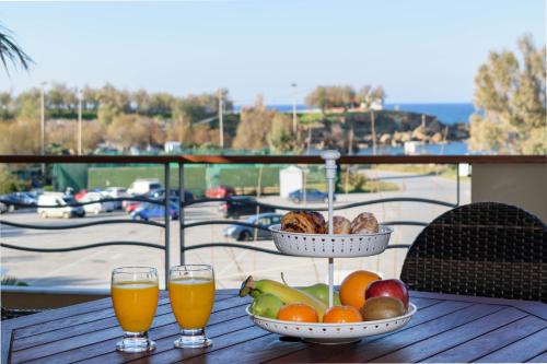Xenios Dias Luxury Apartments With Sea View في كاتو داراتسو: طاولة مع الفاكهة وكأسين من عصير البرتقال