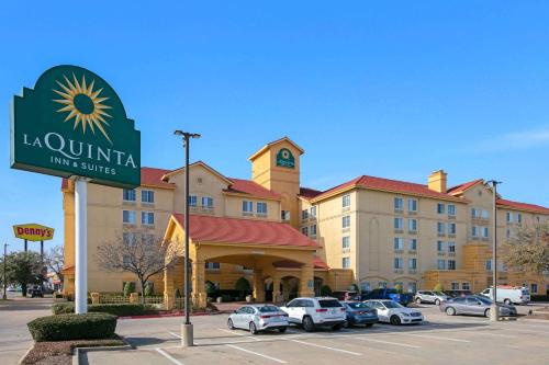 una señal para un hotel con coches estacionados en un estacionamiento en La Quinta by Wyndham DFW Airport South / Irving, en Irving