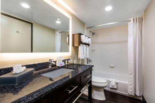 a bathroom with a sink and a toilet and a mirror at La Quinta by Wyndham San Diego Mission Bay in San Diego