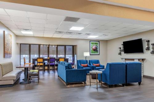 a waiting room with blue chairs and tables and a tv at Comfort Inn & Suites Clemson - University Area in Clemson