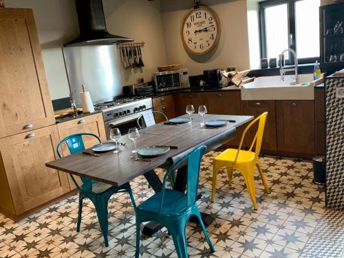 une cuisine avec une table, des chaises et une horloge murale dans l'établissement Gîte La Maison de Françoise, à Vinon