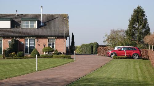 a red car parked in front of a house at B&B Bij Bronckhorst in Steenderen