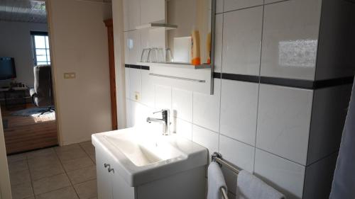 La salle de bains blanche est pourvue d'un lavabo et d'un miroir. dans l'établissement B&B Bij Bronckhorst, à Steenderen