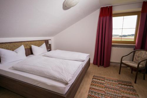 um quarto com uma cama, uma cadeira e uma janela em Ferienwohnungen Chiemgauer Seenglück em Obing