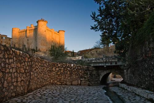 una pared de piedra con un puente y un castillo en Hotel Rural El Salero, en Torija