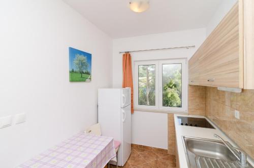 a kitchen with a white refrigerator and a window at Apartments Vinko in Sobra