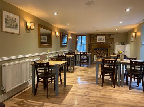 um restaurante com mesas e cadeiras e uma lareira em The Covenanter Hotel em Falkland