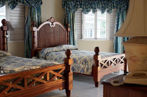 a bedroom with two beds with blue curtains at Beachcomber Club Resort in Negril