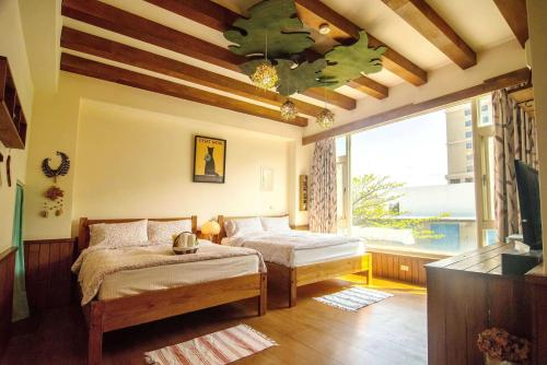 花蓮市にあるSeville Countrified B&Bのベッドが2つと大きな窓がある寝室