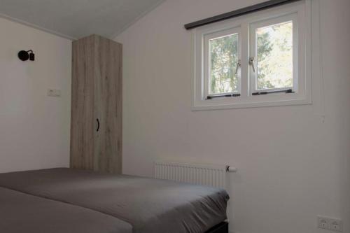 una camera con letto e finestra di Huisjes Putten Reewold luxe chalet in rustige en mooie omgeving a Putten