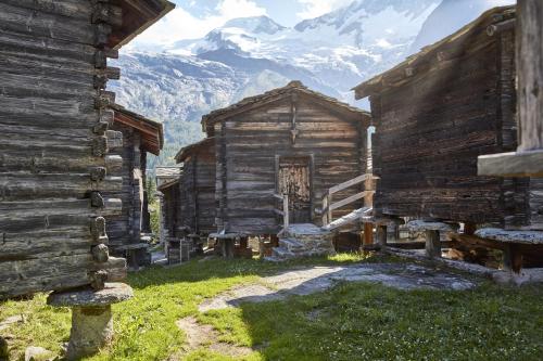 um antigo chalé de madeira com montanhas ao fundo em Haus Holiday em Saas-Fee