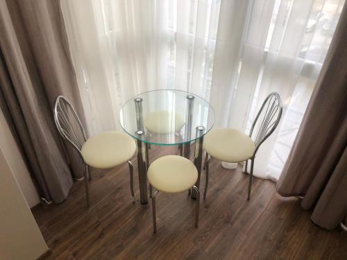 a glass table and four chairs in front of a window at Квартира с двумя комнатами в Ж/К Атлант (ул. Антоновича 36Д) in Dnipro