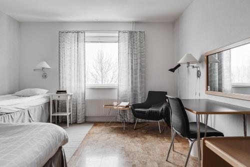 a hotel room with a bed and a desk and chairs at Medlefors Hotell & Konferens in Skellefteå