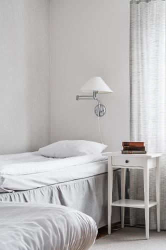 a white bedroom with a bed and a table at Medlefors Hotell & Konferens in Skellefteå