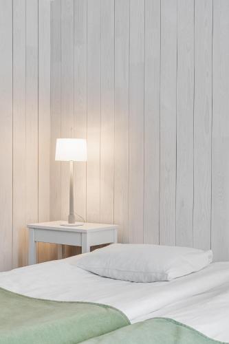 a bedroom with a bed and a table with a lamp at Medlefors Hotell & Konferens in Skellefteå