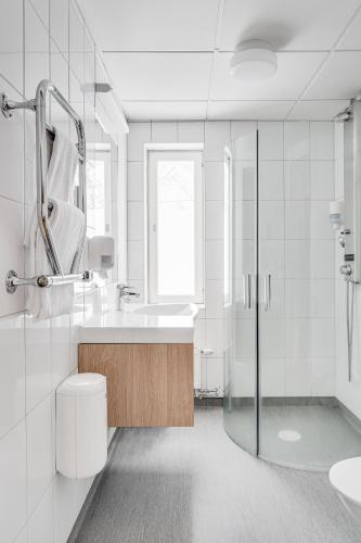 a white bathroom with a sink and a shower at Medlefors Hotell & Konferens in Skellefteå