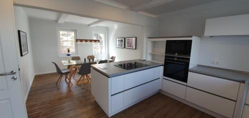 Una cocina con gabinetes blancos y una mesa con sillas. en Ferienhaus Südwesthörn, en Emmelsbüll-Horsbüll
