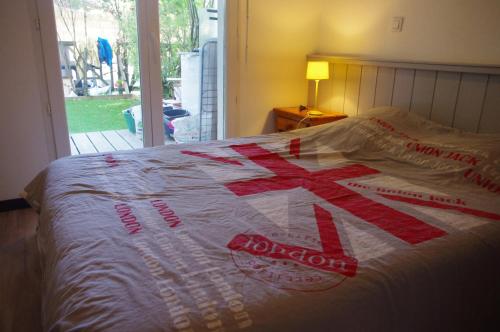 a bed with a red and white quilt on it at Bassin d'Arcachon Ares Charmant T2 jardin in Arès