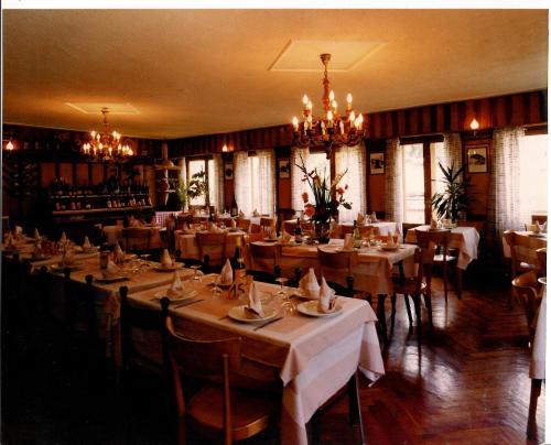 un ristorante con tavoli, sedie e lampadario a braccio di Hotel Beau Sejour a Etroubles