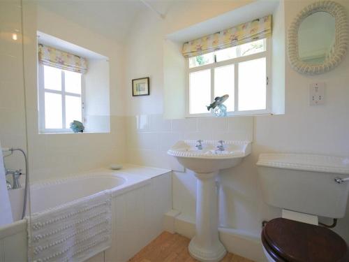 a white bathroom with a sink and a tub and a toilet at Mayfly Cottage in Quenington