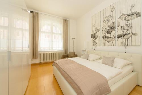 ein weißes Schlafzimmer mit einem Bett und einem Gemälde an der Wand in der Unterkunft Fewo auf der Dominsel-LOTUS in Brandenburg an der Havel