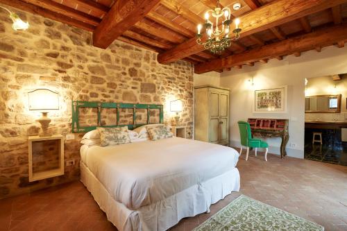 a bedroom with a large bed and a stone wall at Podere di Moiata in Campestri