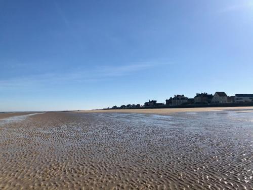 a sandy beach with water and buildings in the background at La Villa Port Winston - Face Mer B&B in Saint-Côme-de-Fresné