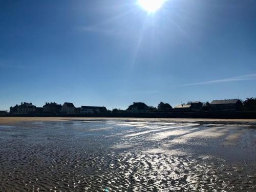 a beach with the sun shining on the sand at La Villa Port Winston - Face Mer B&B in Saint-Côme-de-Fresné