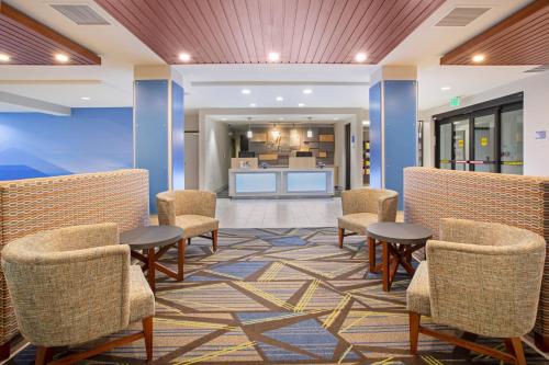a lobby with chairs and tables and a kitchen at Holiday Inn Express & Suites Phoenix Glendale Dist by IHG in Glendale