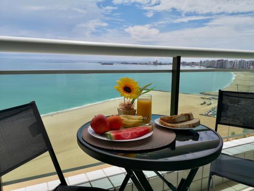 einen Obstteller auf einem Tisch mit Blick auf den Strand in der Unterkunft Modern Beachfront Apartment w. Magnificent Seaview in Fortaleza