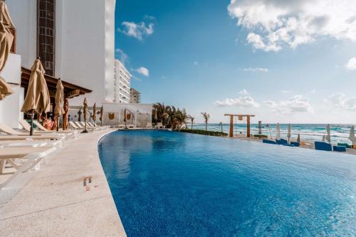 a pool at a resort with chairs and the ocean at Ocean Dream Cancun by GuruHotel in Cancún