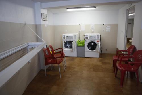 a laundry room with a washer and dryer and red chairs at Zendoira in Palas de Rei