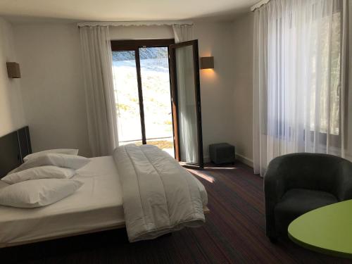 1 dormitorio con 1 cama, 1 silla y 1 ventana en La maison de Cécile, en Ventron