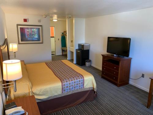a hotel room with a bed and a flat screen tv at Airport Inn in South San Francisco