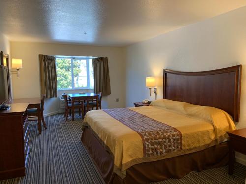 a hotel room with a bed and a table at Airport Inn in South San Francisco