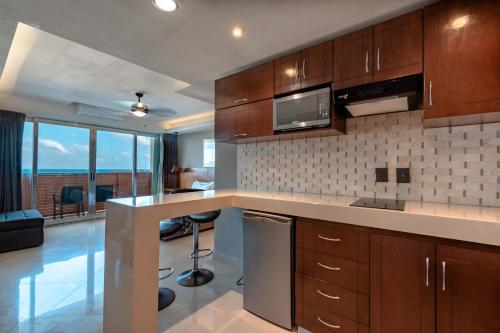 a kitchen with wooden cabinets and a counter top with a television at Ocean Dream Cancun by GuruHotel in Cancún